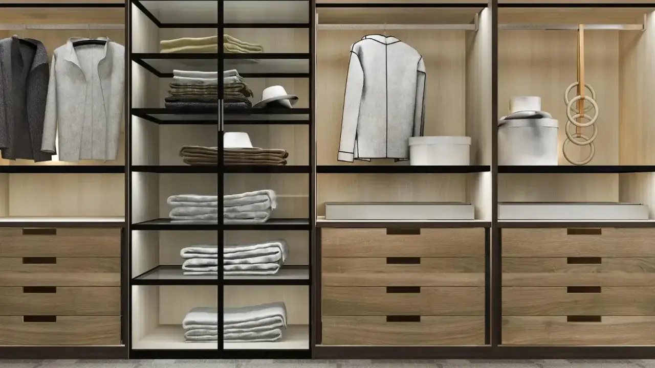 Un moderno armario empotrado con puertas de cristal y madera, organizado con ropa doblada, colgada y accesorios.