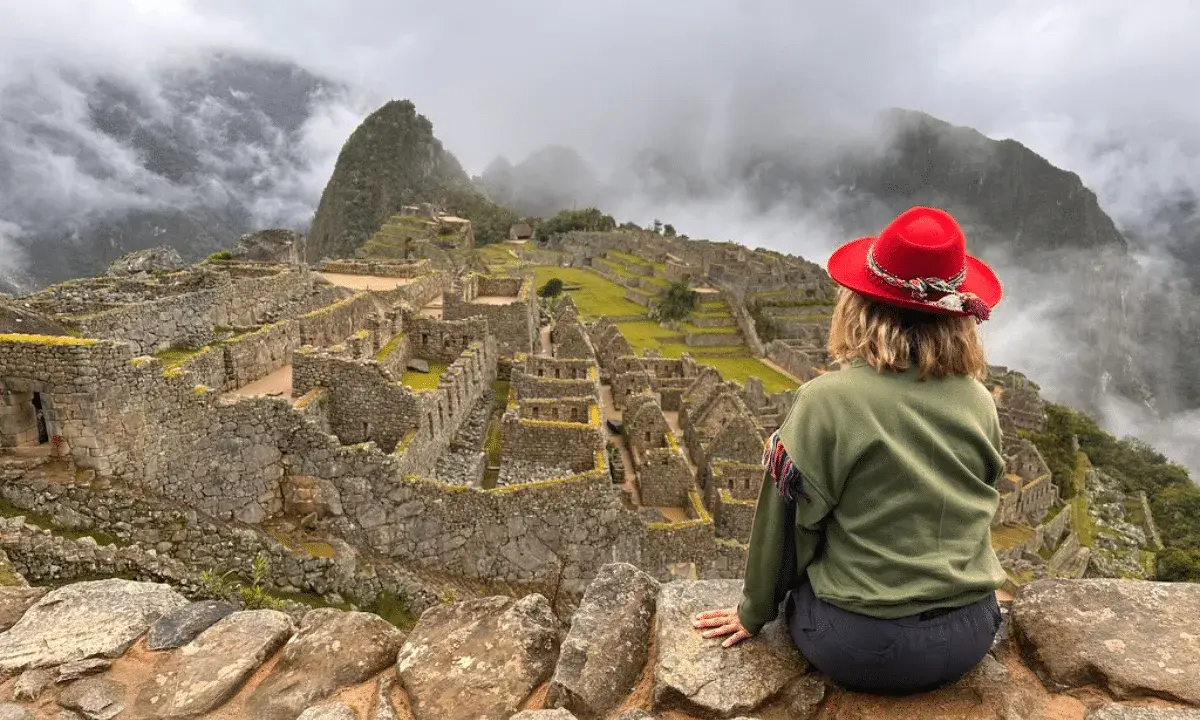 Kobieta w czerwonym kapeluszu podziwia Machu Picchu. Czy w Peru jest bezpiecznie? Tak, to bezpieczna podróż do serca Inków.