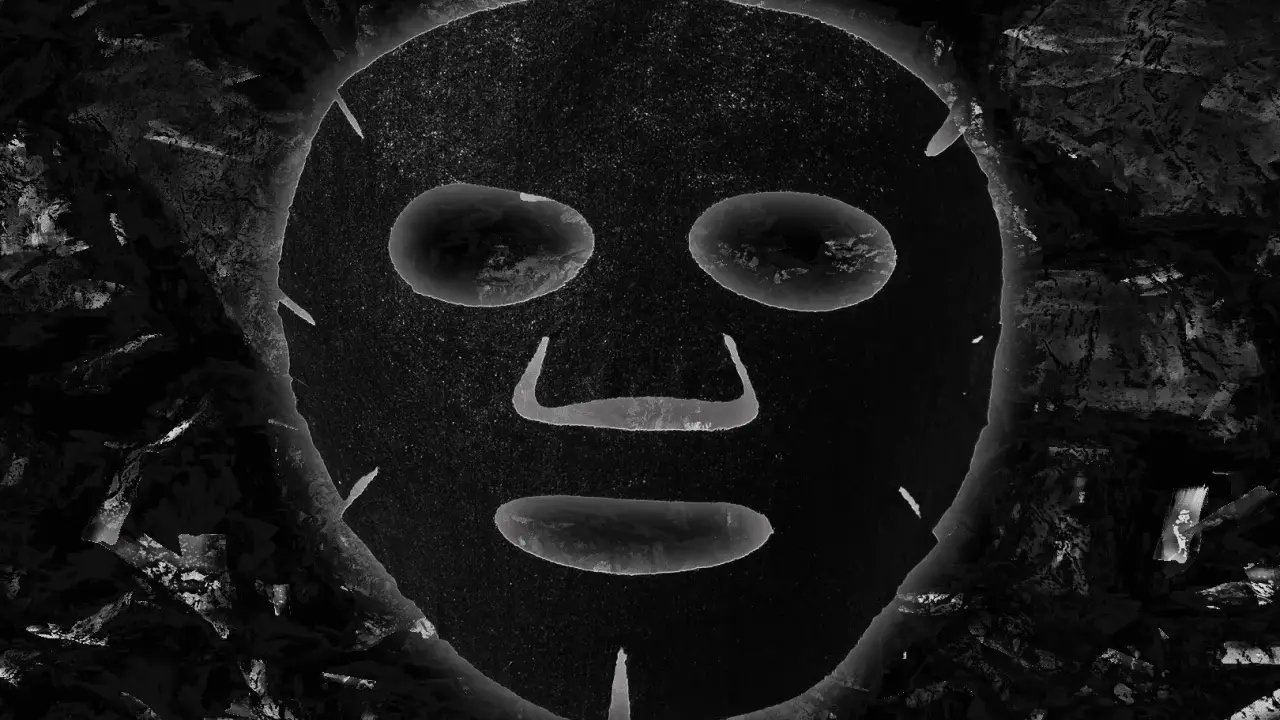 Maschera al carbone, con i suoi benefici, appare come un volto misterioso incorniciato da texture scure e profonde.