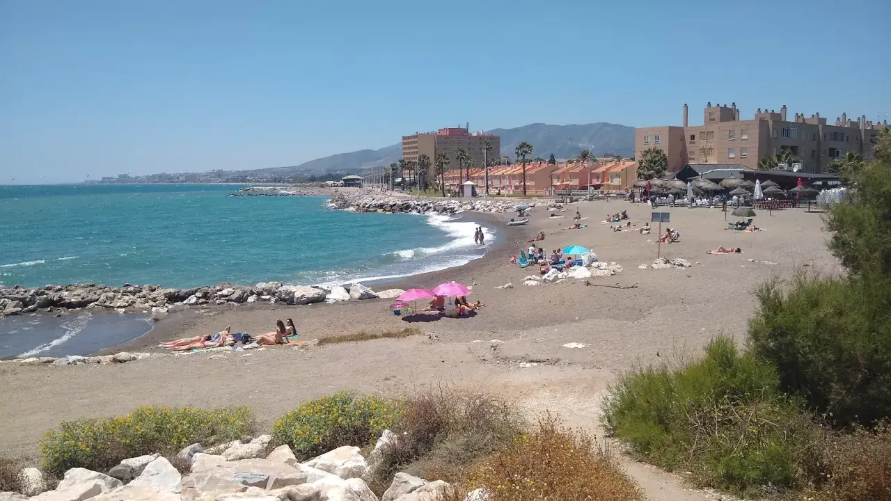 Sonniger Tag am playa de guadalmar mit Menschen, die sich am Strand sonnen und im türkisfarbenen Meer schwimmen.
