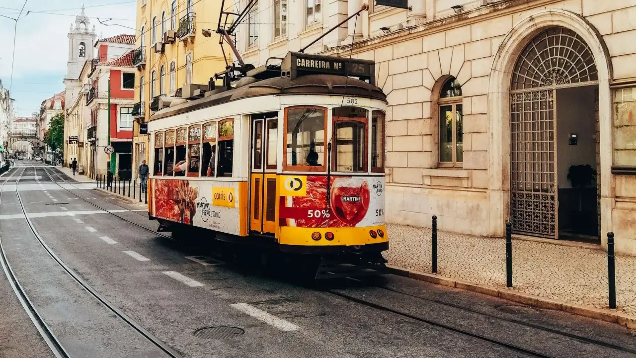 Gelbes Tram fährt durch Lissabon. Perfekt für eine Erkundungstour beim Lissabon wandern.