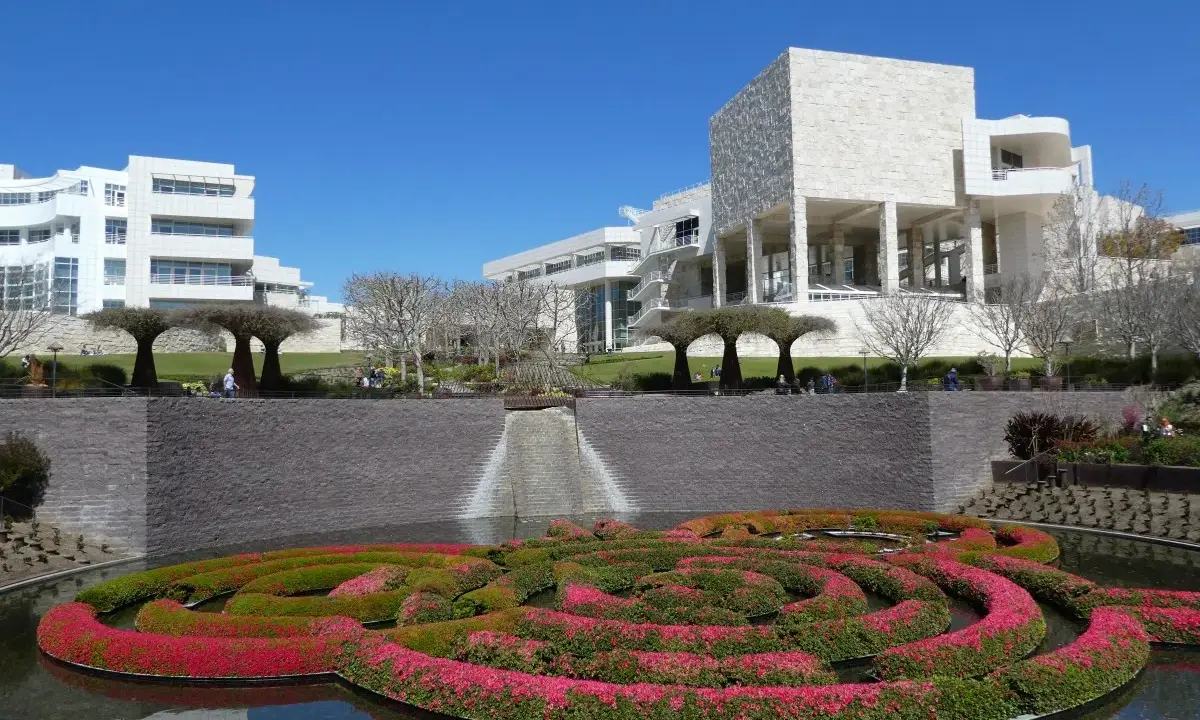 A vibrant floral maze floats in a pool before the modern architecture of the Los Angeles Center for Digital Art.