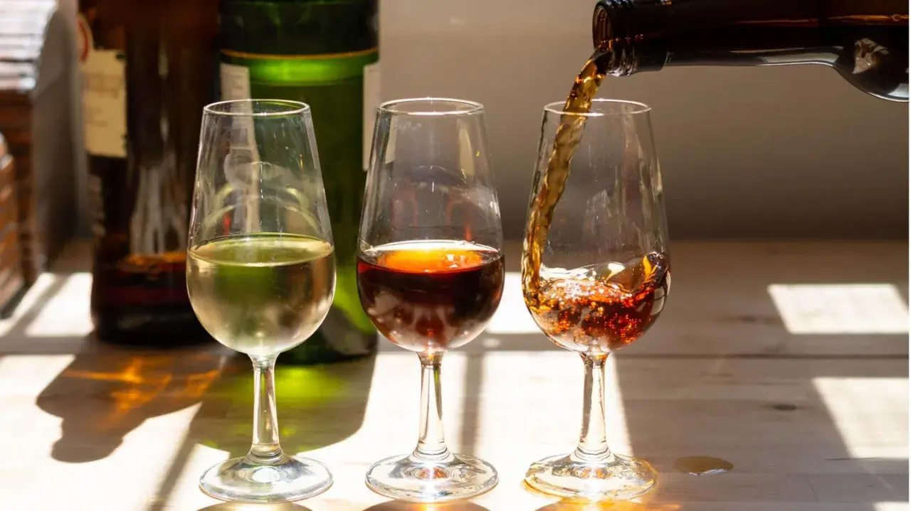 Drei Gläser mit Sherry, die die Vielfalt der sherry Herkunft zeigen. Ein helles, ein dunkles und ein drittes, das gerade eingeschenkt wird.