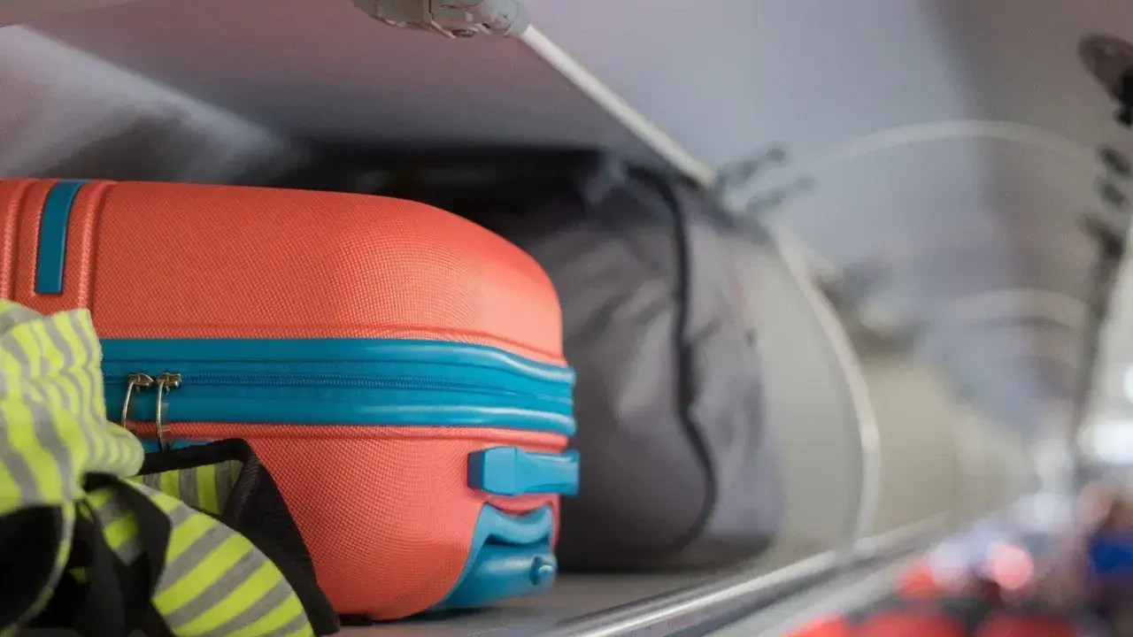 Pomarańczowa walizka i szara torba jako flydubai bagaż podręczny w schowku nad siedzeniami.