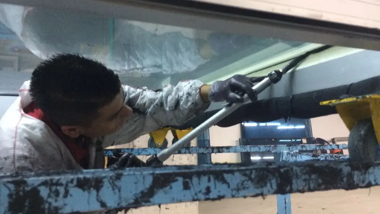 Un trabajador aplica **silicona estructural** en una junta de ventana.