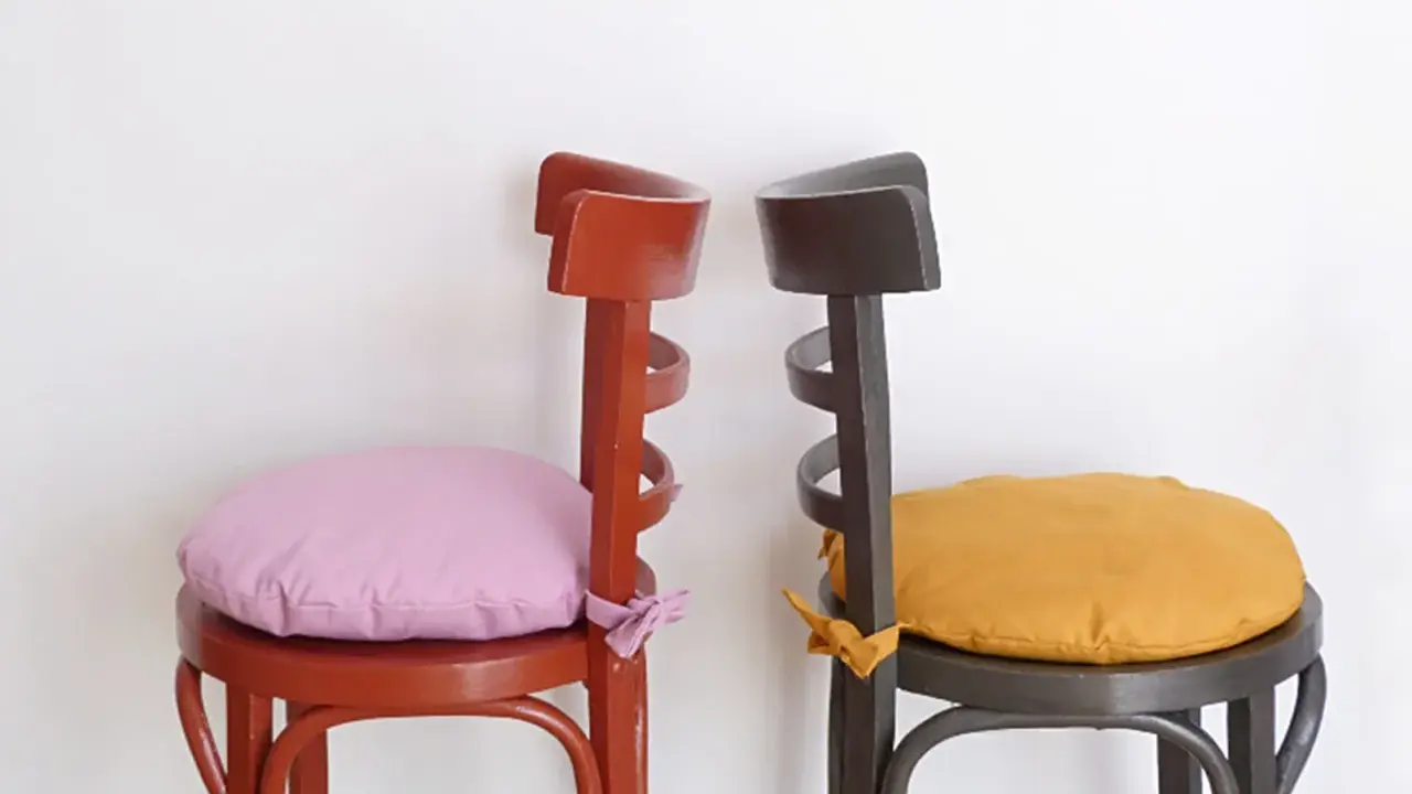 Dos sillas de madera pintadas, una roja con cojín lila y otra gris con cojín ocre. ¡Ideas para pintar sillas de madera!