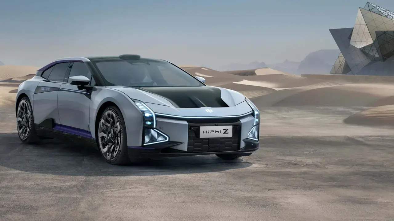 Futuristisches Elektroauto HiPhi Z in silber mit lila Akzenten, steht in einer Wüstenlandschaft vor einer modernen Glasarchitektur.