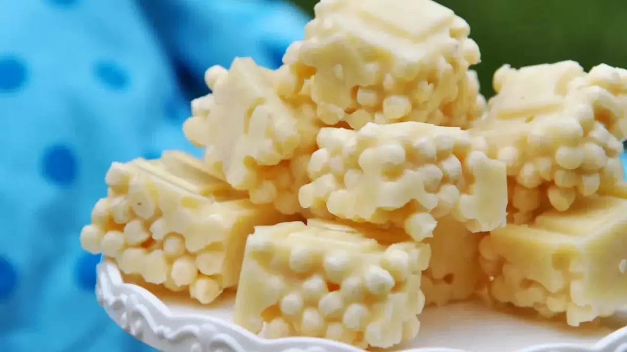 Leckere zuckerfrei leben rezepte: weiße Schokoladenstücke mit knusprigen Reispops auf einem weißen Teller.