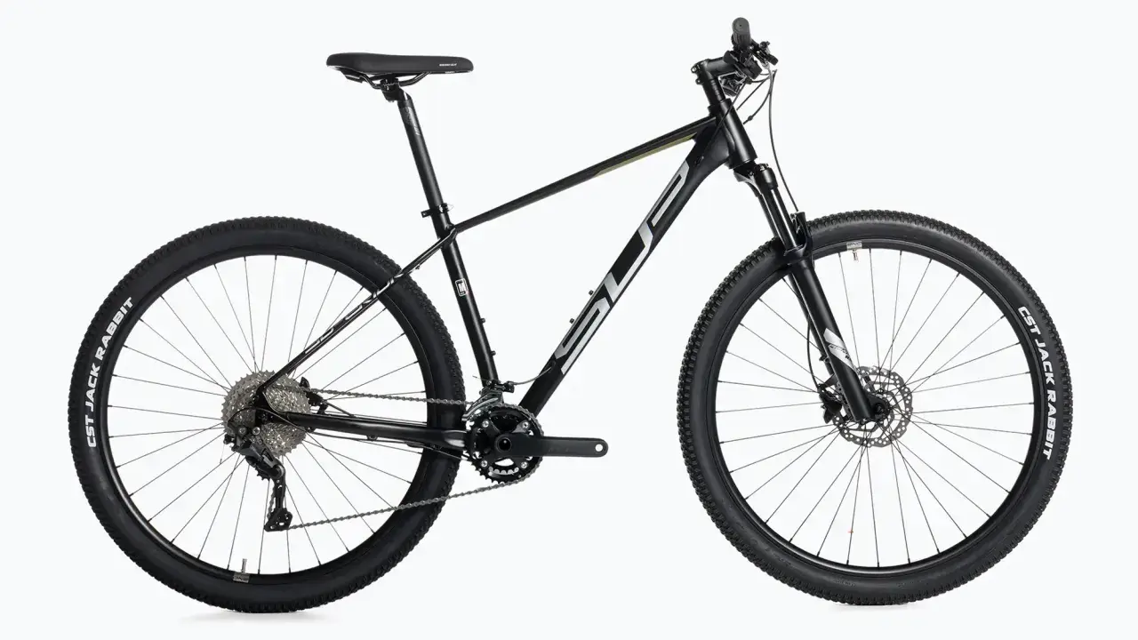 Czarny rower górski, idealny do wyścigów mtb xc. Wyposażony w amortyzator, przerzutki i opony CST Jack Rabbit.