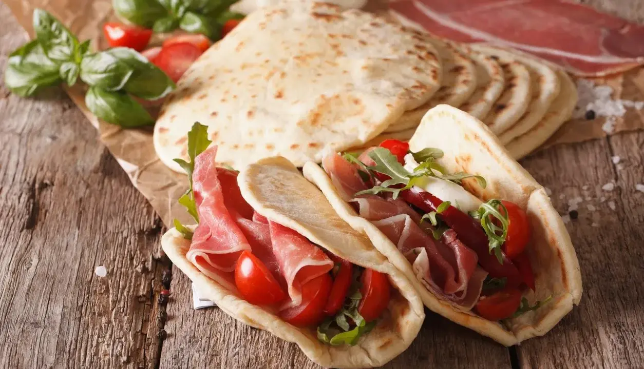 Piadina romagnola, un piatto tipico di Rimini, farcita con prosciutto crudo, pomodorini e rucola.