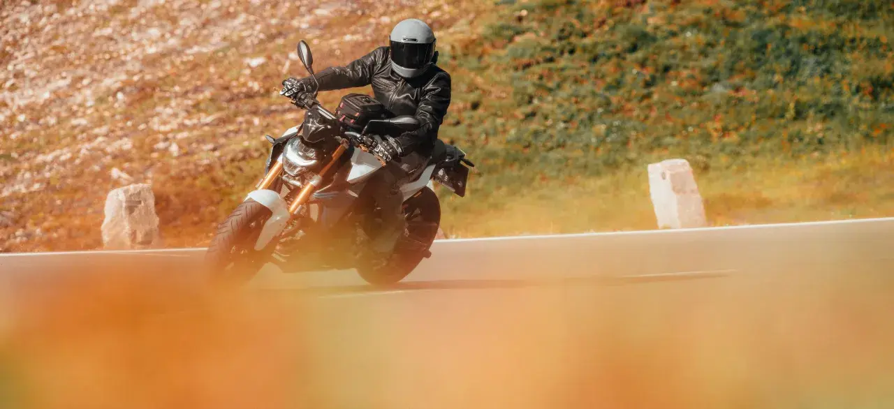 Motociclista con casco y chaqueta de cuero en una moto deportiva, disfrutando de la carretera. Ideal para quienes buscan el permiso conducir A1.