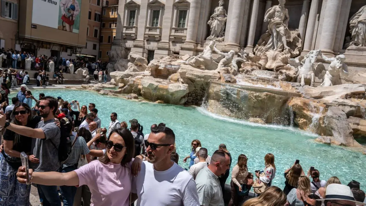 Foule de touristes admirant la fontaine de Trevi, la fontaine de l'amour à Rome, prenant des selfies devant les statues majestueuses et l'eau turquoise.