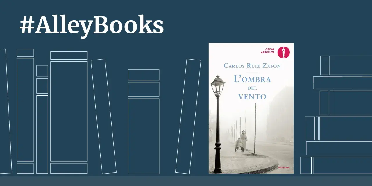 Copertina del libro "L'ombra del vento" di Carlos Ruiz Zafón, con un'immagine suggestiva di una strada nebbiosa e due figure.