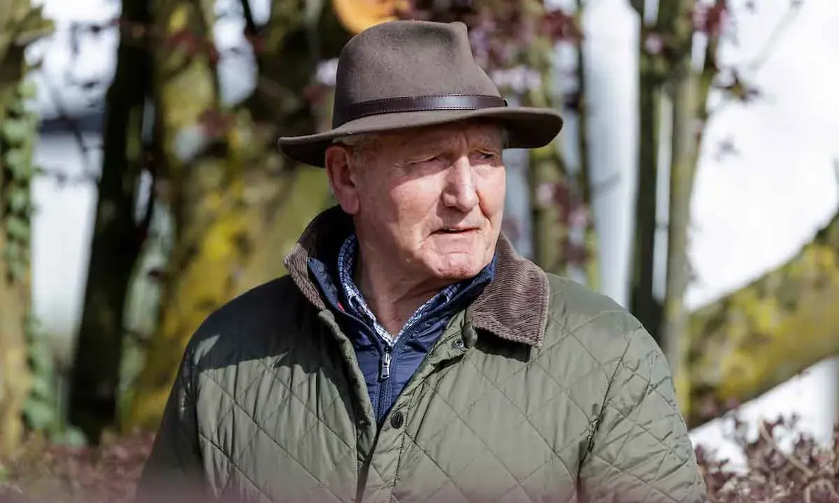 Klaus Balkenhol, ein älterer Herr mit Hut und Steppjacke, blickt nachdenklich in die Ferne.