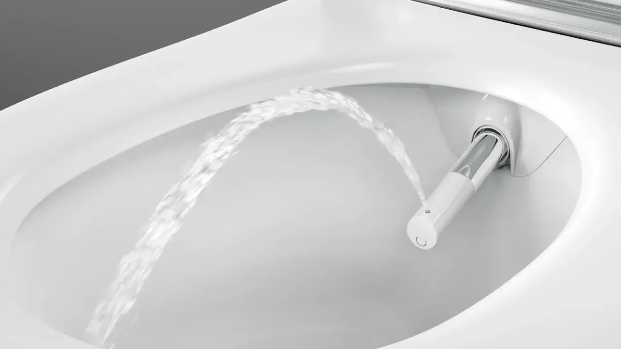 Chorro de agua saliendo de un inodoro moderno, mostrando la función de ducha integrada. Es como si el inodoro tuviera su propio bidet para quitar impurezas.
