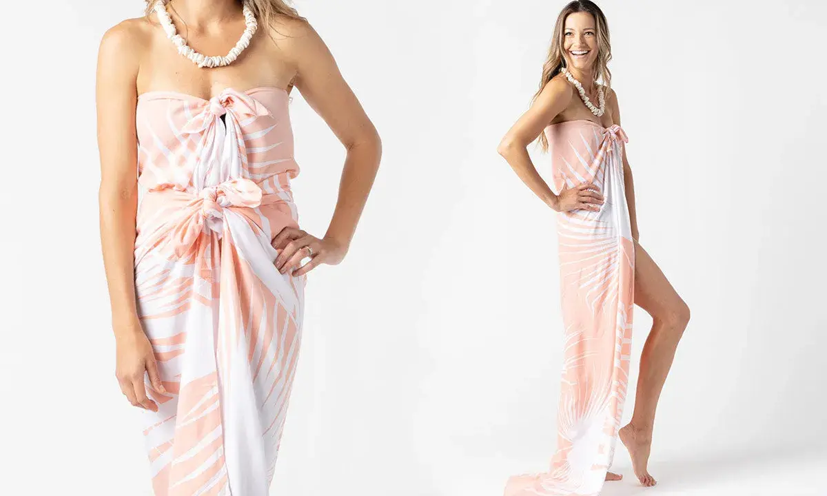 Modella mostra come indossare un pareo con fantasia tropicale, annodato in vita e al seno, con una collana di conchiglie.