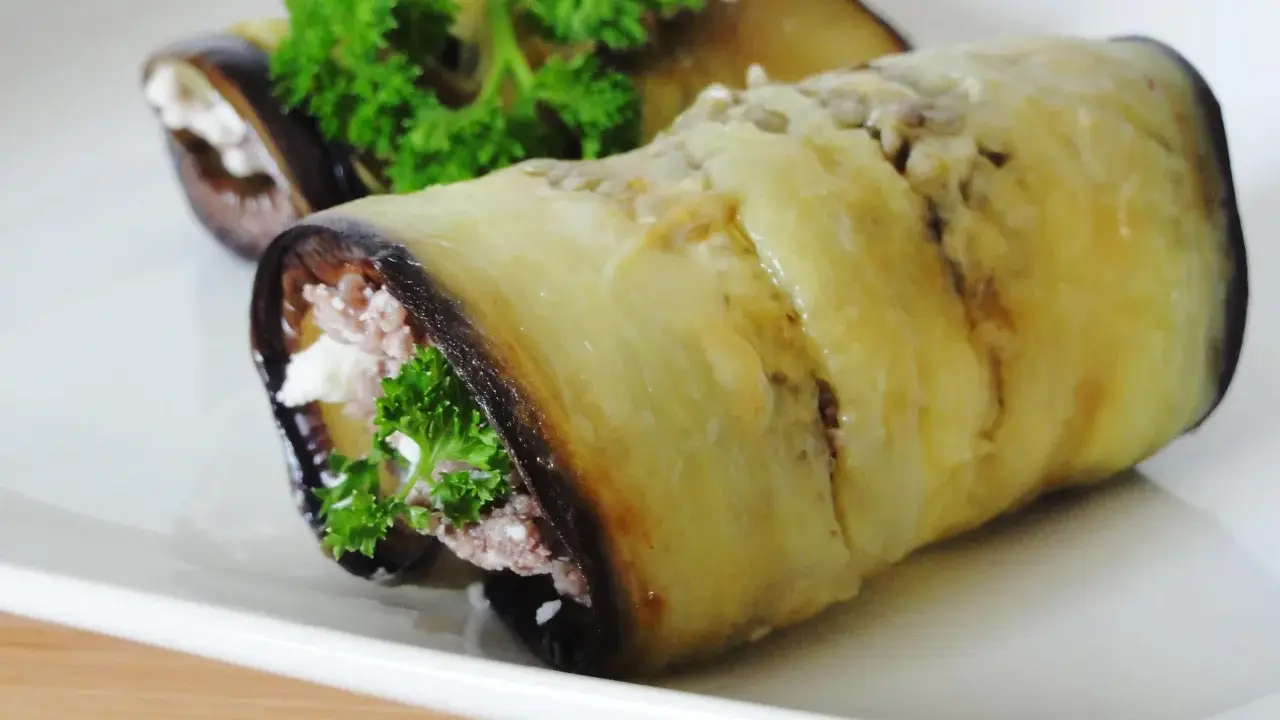 Rouleaux d'aubergine farcie au fromage et aux herbes, garniture appétissante.