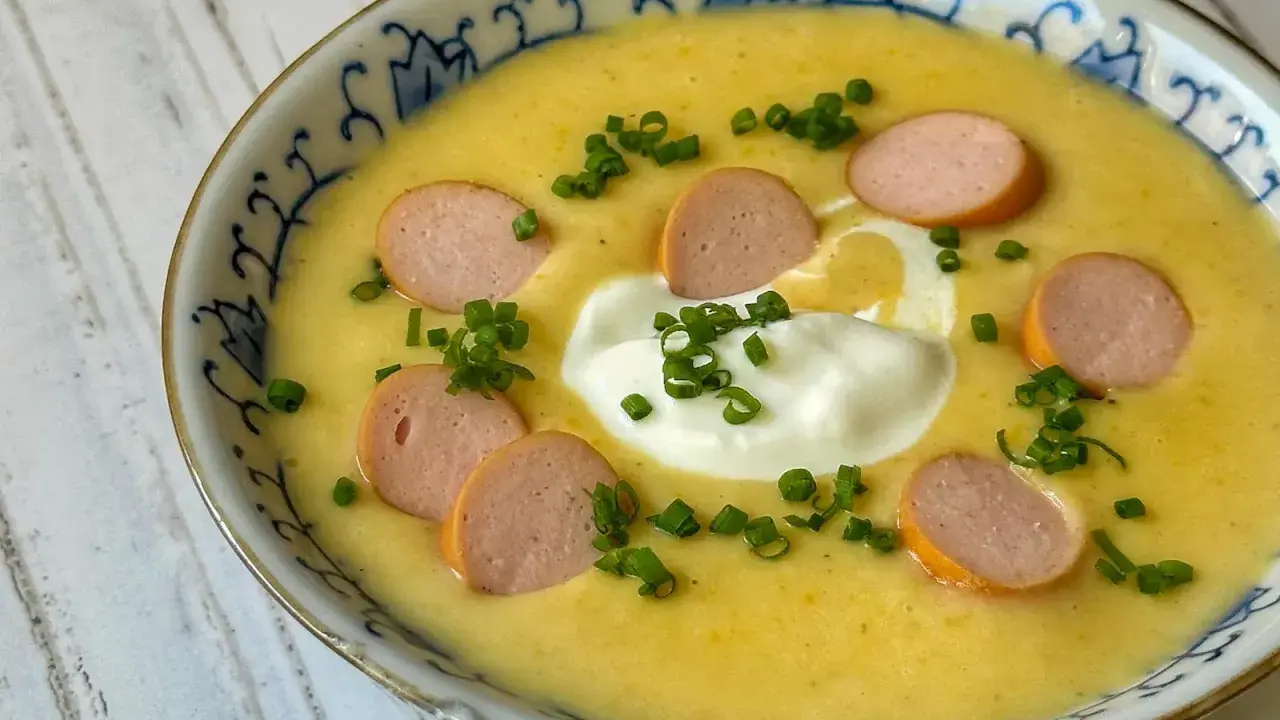 Cremige Kartoffelsuppe mit Würstchenscheiben, einem Klecks Sahne und Schnittlauch. Ein einfaches und leckeres Kartoffelsuppe Rezept für kalte Tage.