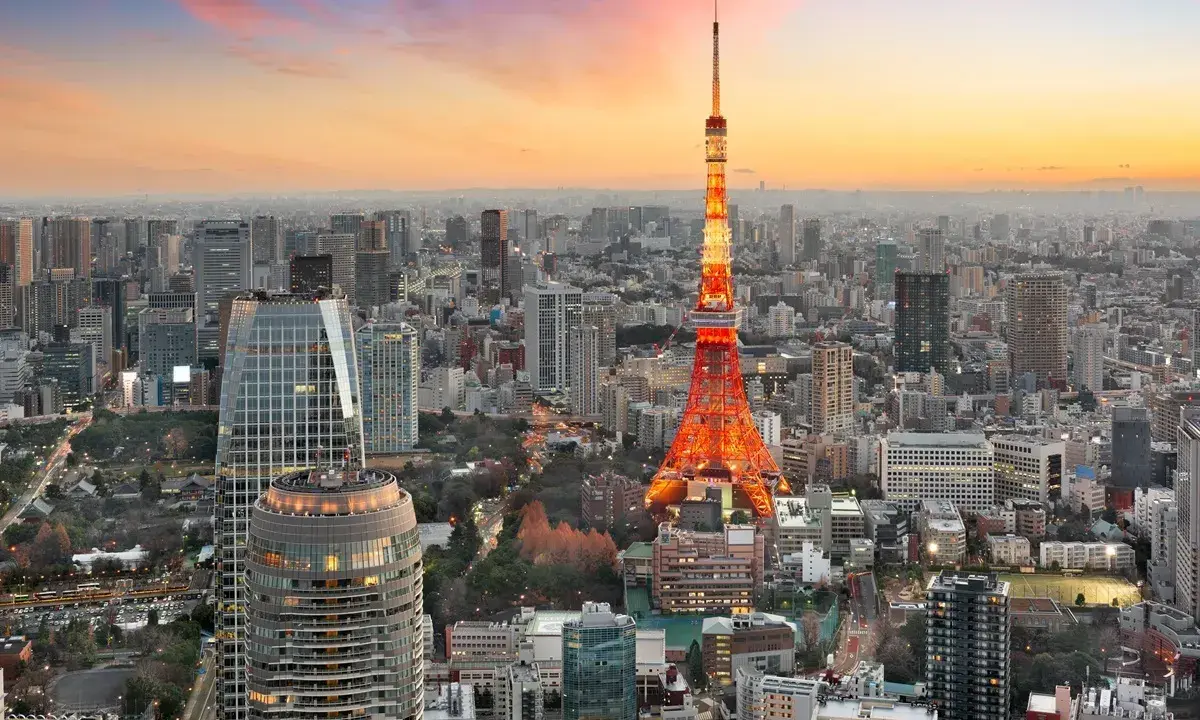 Widok na Tokio, największe miasto na świecie, z wieżą Tokyo Tower w pomarańczowych barwach o zachodzie słońca.