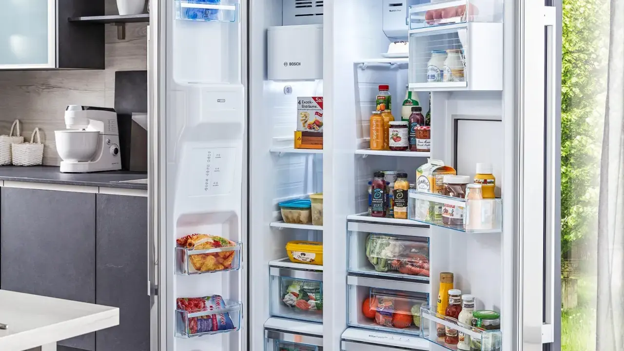 Offener Kühlschrank mit Lebensmitteln, darunter gefrorene Produkte und Getränke. Die Temperatur im Gefrierschrank ist ideal für die Lagerung.