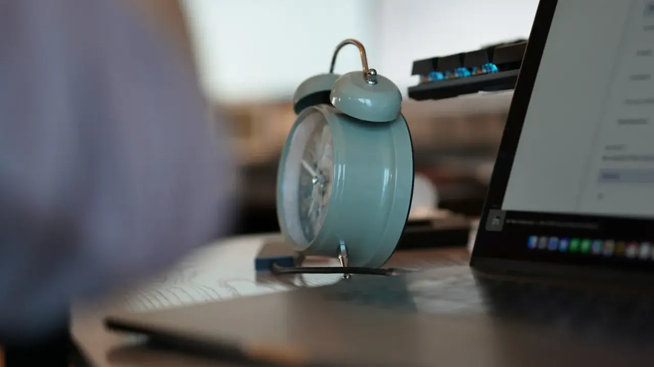 Budzik obok laptopa i klawiatury. Czas na pracę na 3/4 etatu.