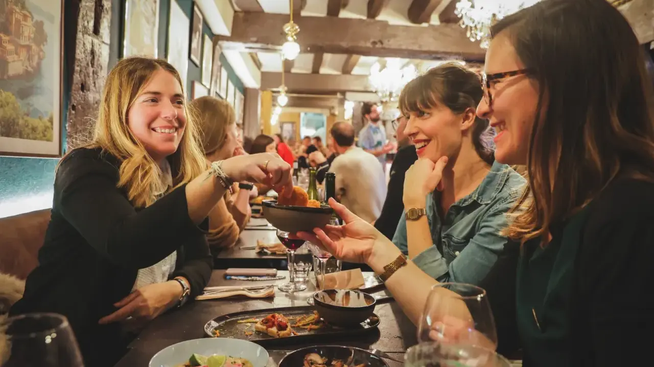 Amies joyeuses partageant des tapas dans un resto ouvert le dimanche à Rennes. Ambiance chaleureuse et conviviale.