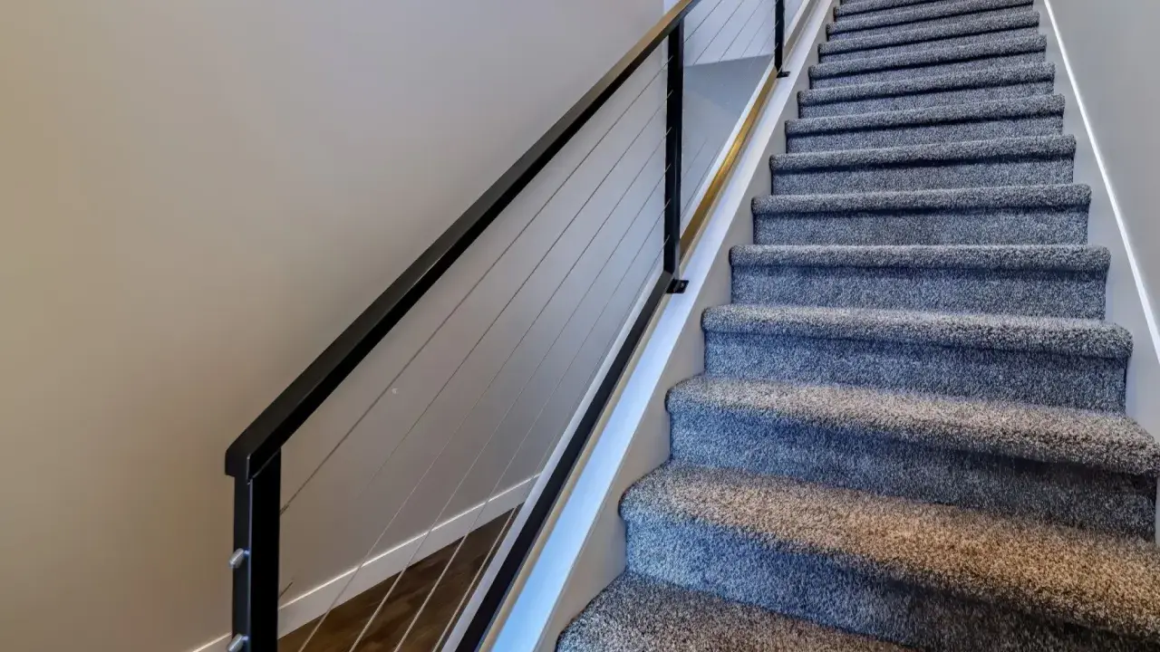 Miękka wykładzina na schody betonowe zapewnia komfort i bezpieczeństwo. Nowoczesna balustrada z linkami dodaje elegancji.