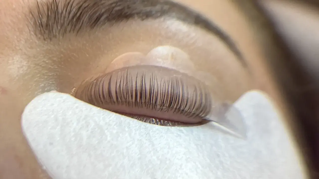 Un œil fermé, les cils recourbés sur un pad, prêts pour un allongement.