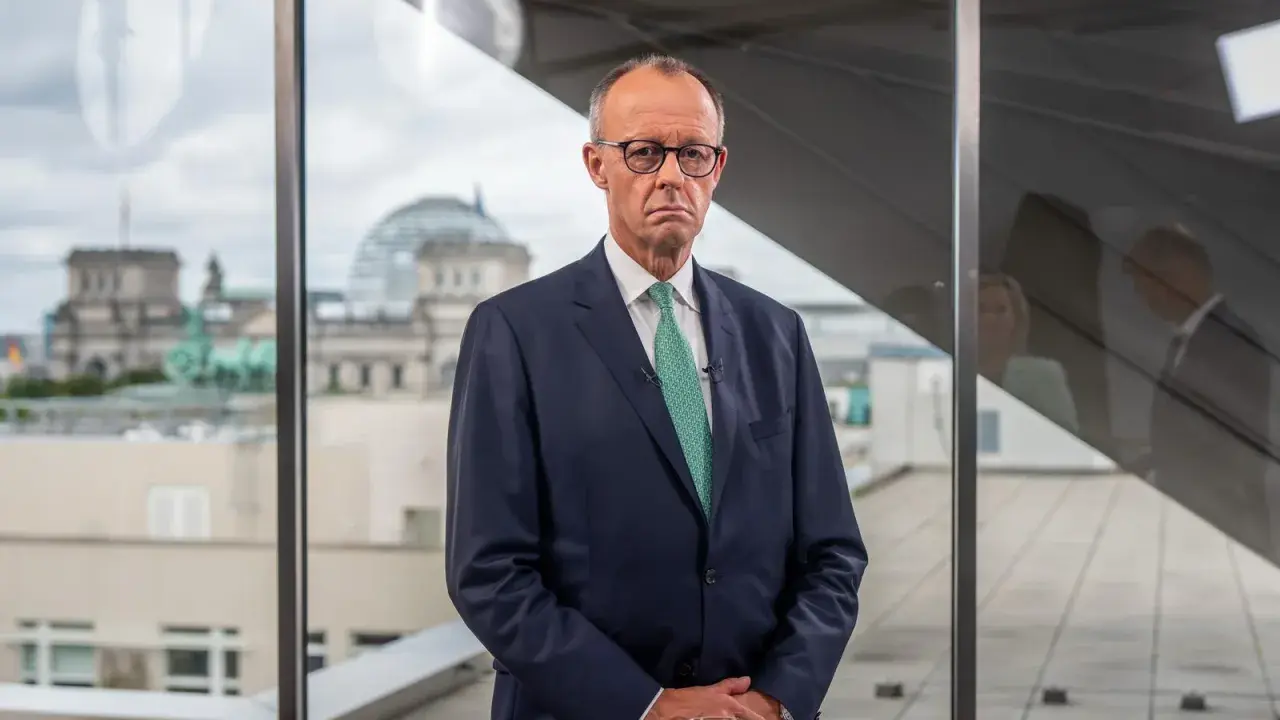 Mann im Anzug blickt nachdenklich, während im Hintergrund das Reichstagsgebäude zu sehen ist. Er spricht über die **Herausforderungen des Sozialstaats**.
