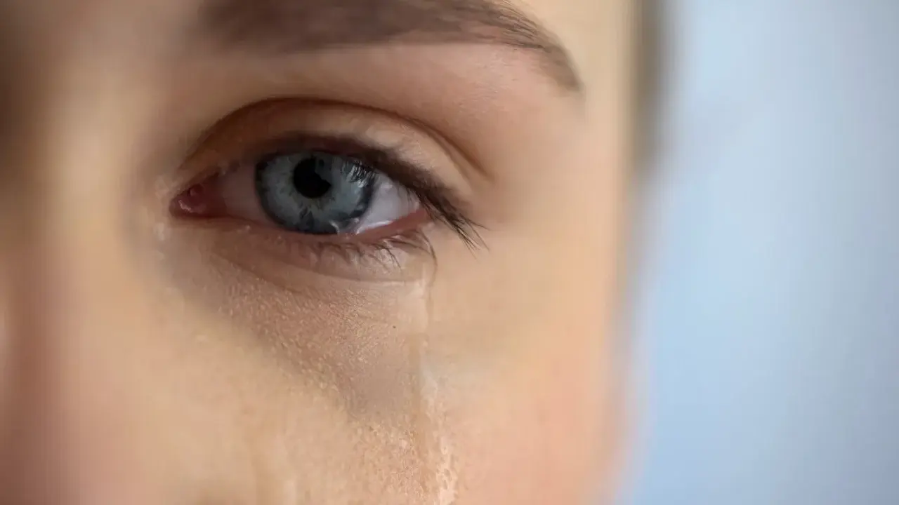 Zbliżenie na niebieskie oko, z którego spływa łza. Scena jak z filmu łzowego, pełna emocji.