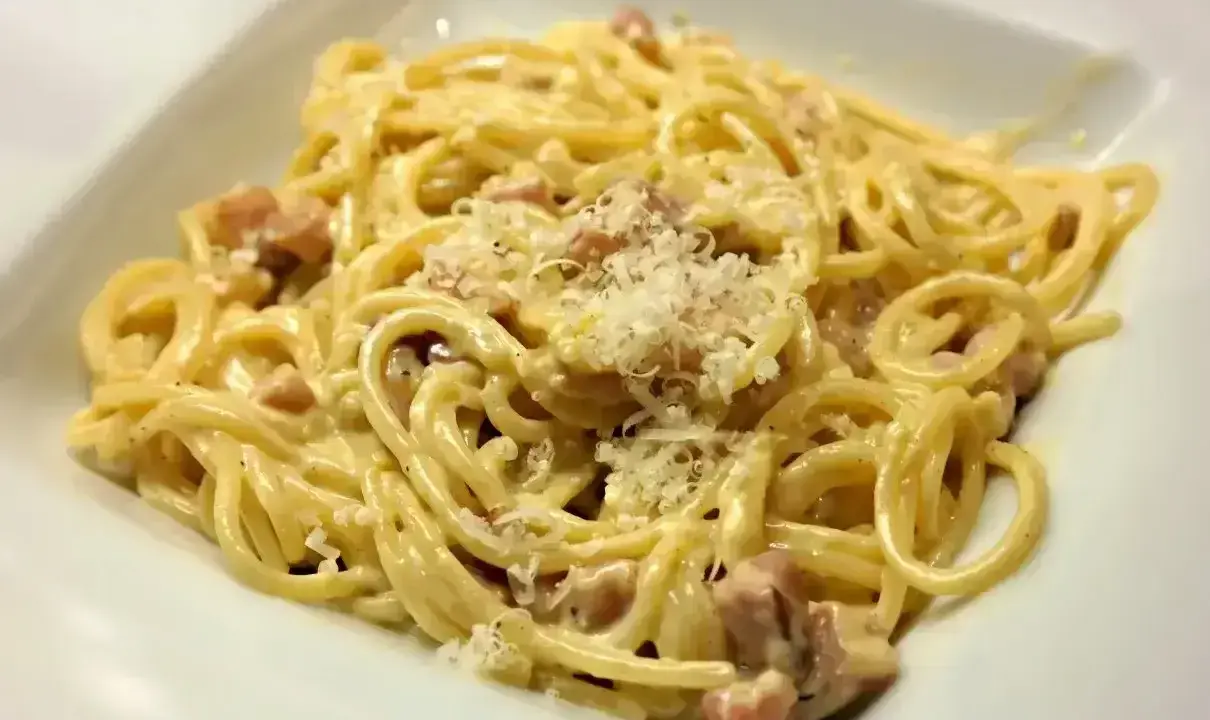 Pyszne spaghetti carbonara z kawałkami boczku i startym parmezanem. Jaki ser do carbonary? Tylko najlepszy!