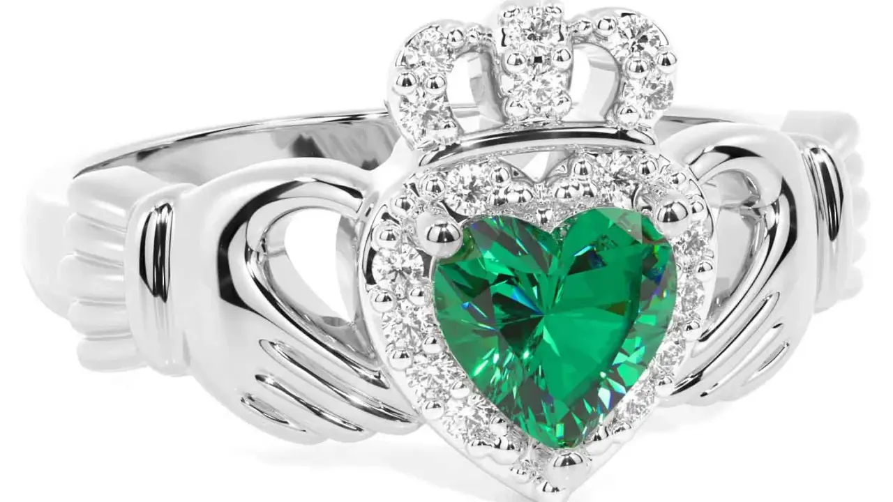Anello Claddagh con cuore verde smeraldo, circondato da diamanti e sormontato da una corona scintillante.