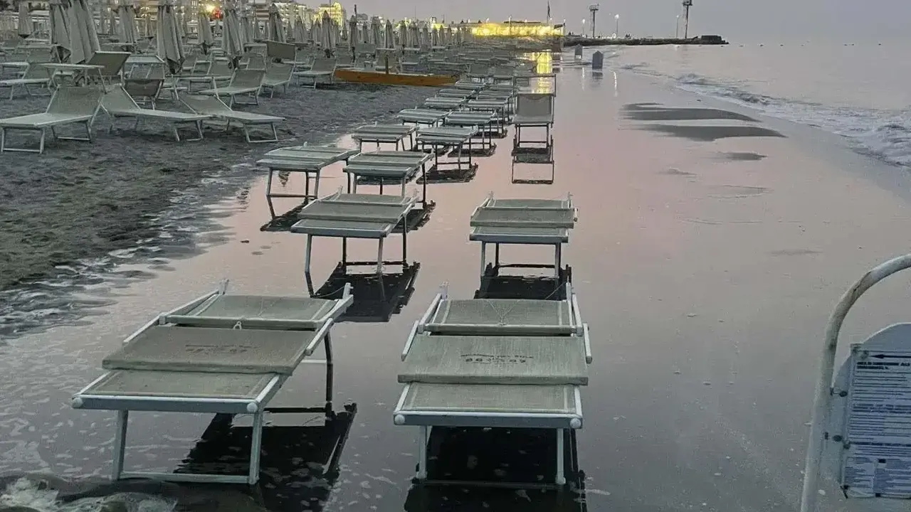 Lettini da spiaggia sommersi dall'acqua a Riccione, con la bassa marea che ha lasciato il segno.