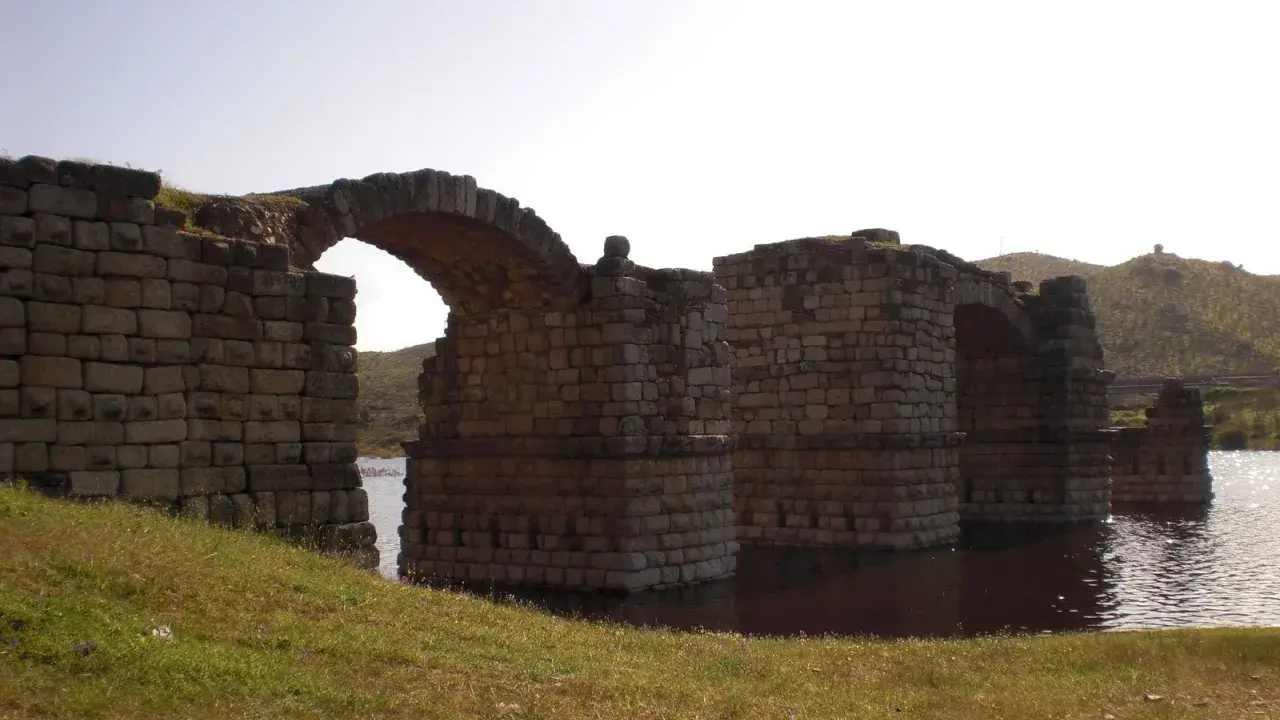 El imponente puente de Alconetar, con sus robustos arcos de piedra, se alza sobre las aguas, testigo de siglos de historia.