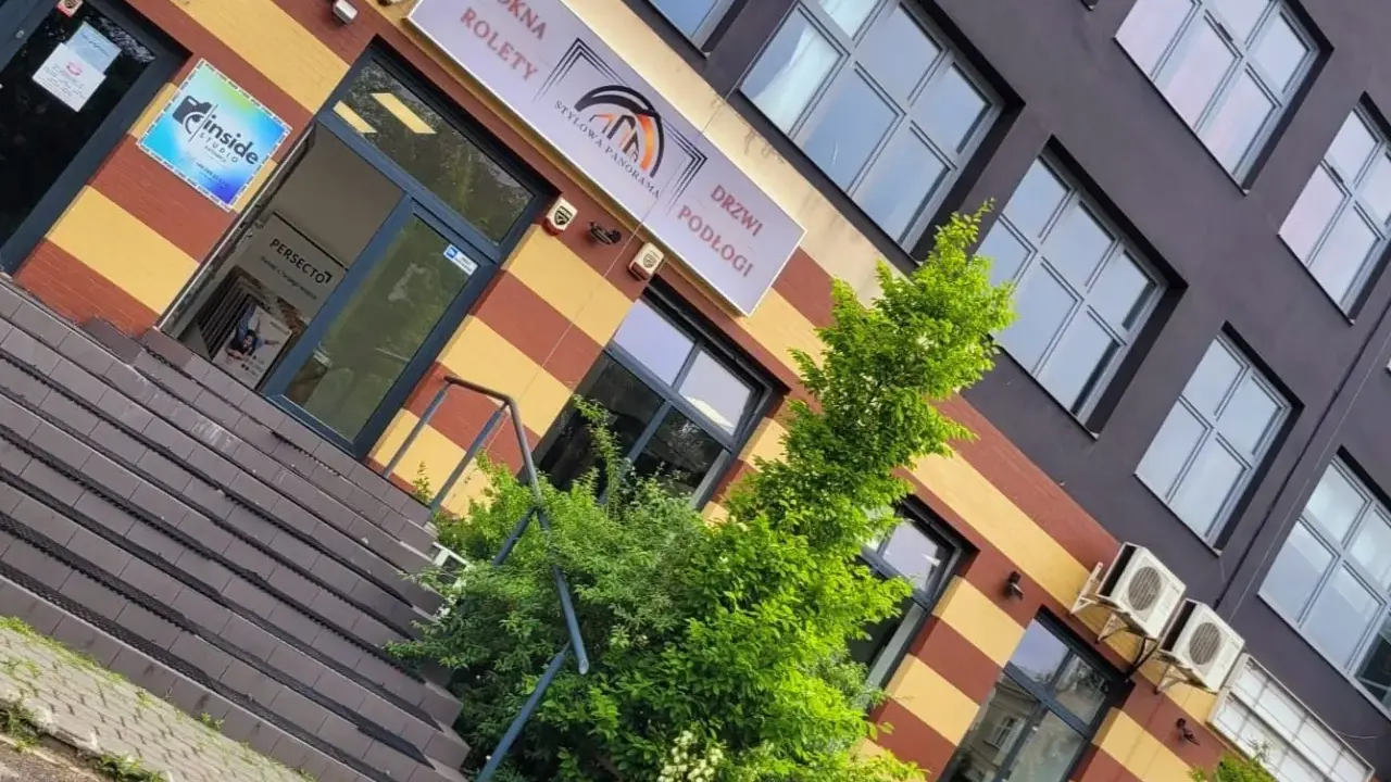 Elegancki budynek z oknami i drzwiami, z zielenią przed wejściem.