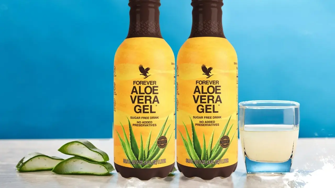 Dwa butelki napoju Forever Aloe Vera Gel, z widocznymi plastrami aloesu i szklanką napoju. Odkryj aloes właściwości.