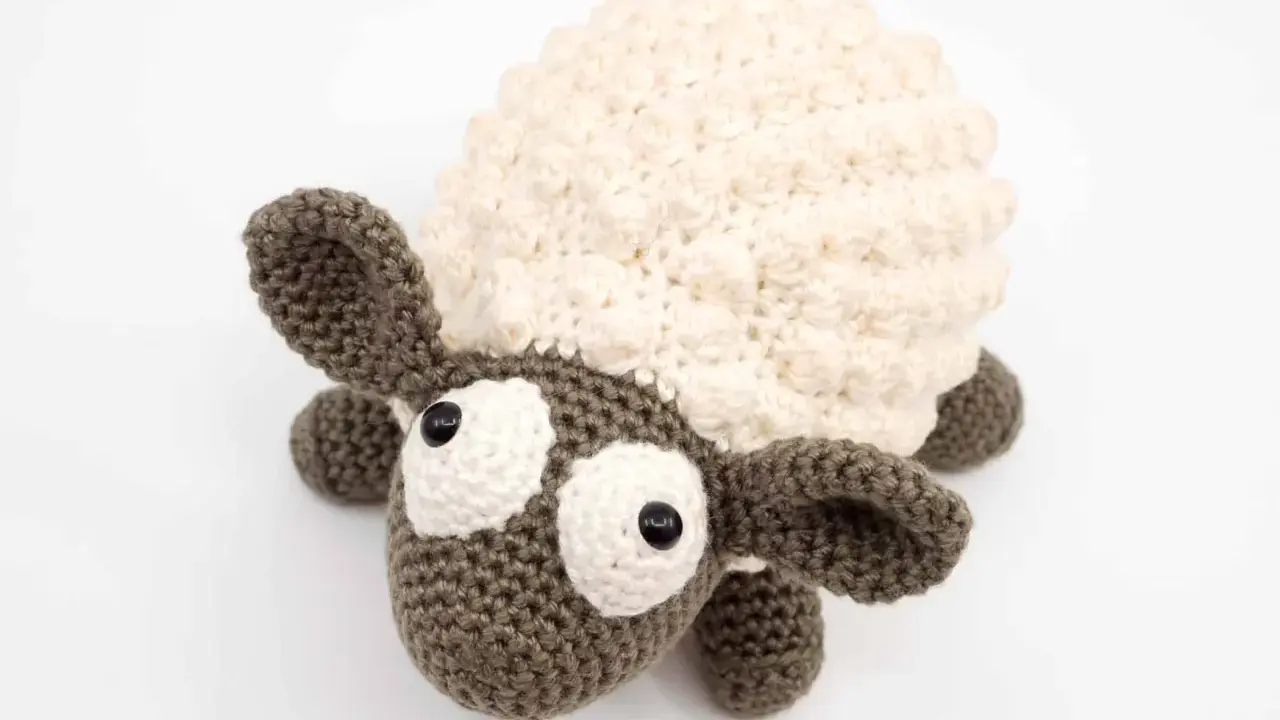 Oveja amigurumi de ganchillo con lana crema y marrón, ojos grandes y expresivos, lista para abrazar.