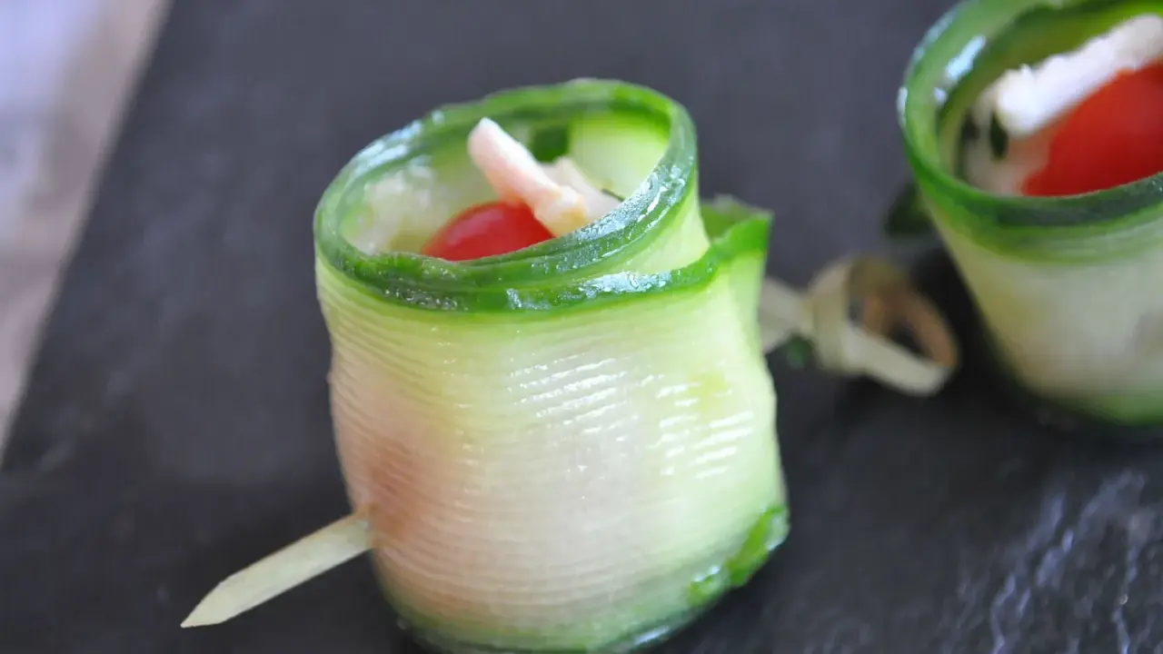 Délicieux wrap apéro de concombre garni de fromage frais, tomate cerise et herbes. Parfait pour un apéritif léger et coloré.