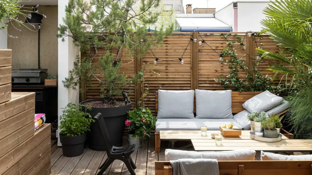 Aménagement terrasse avec pots : un coin salon cosy avec banquette, table basse, et verdure. Parfait pour se détendre.