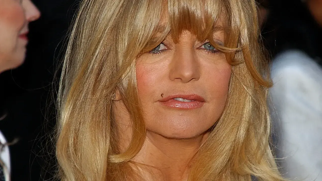 Goldie Hawn ler mot kameran, hennes blonda hår faller runt ansiktet. Tänker på alla roliga filmer med Goldie Hawn.