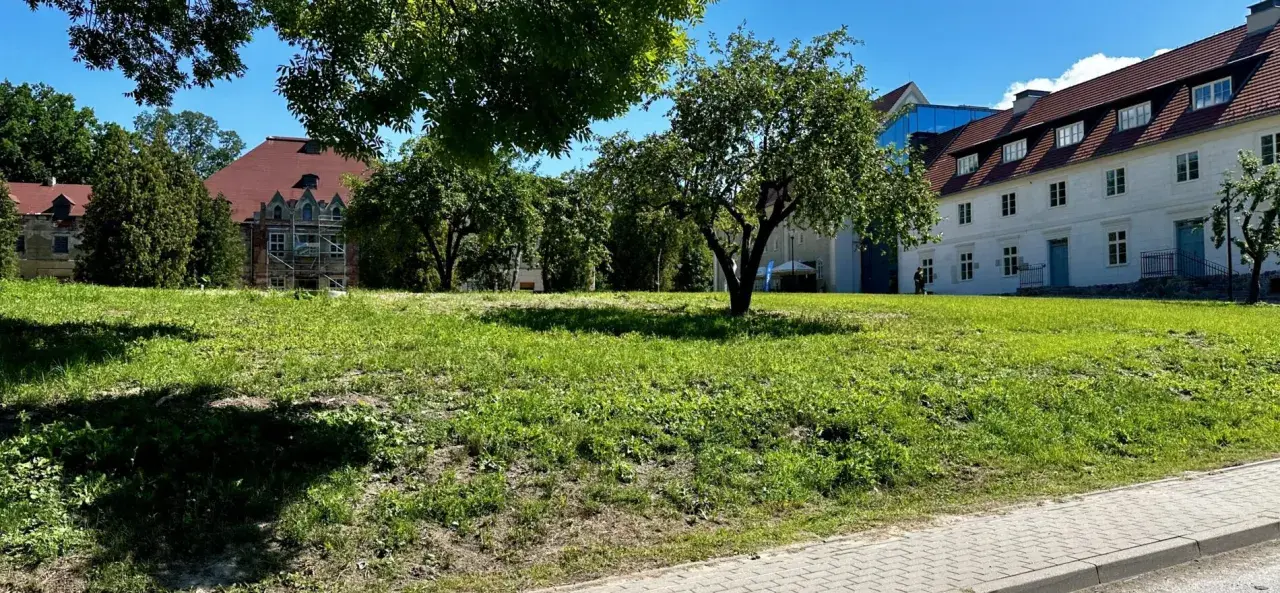 Zielona polana przed zabytkowymi budynkami, idealne miejsce na relaks i odkrywanie sztynort atrakcje.