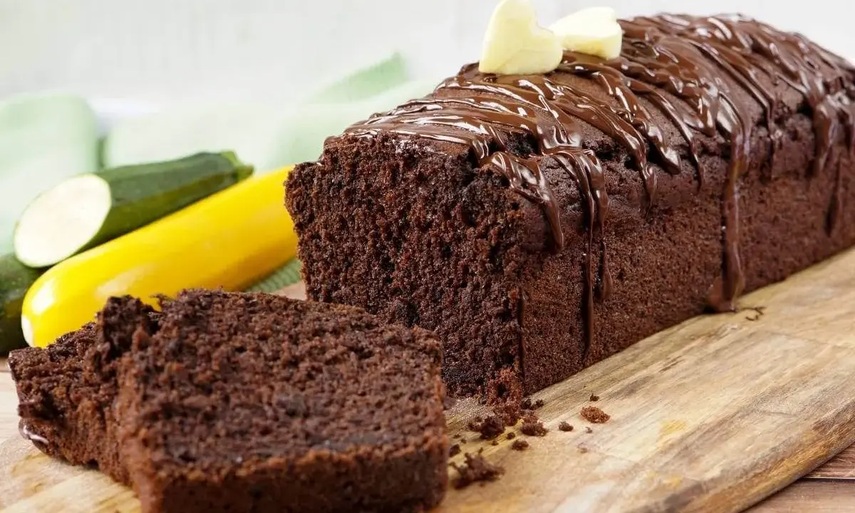 Saftiger schokokuchen mit zucchini, überzogen mit Schokoladenglasur und garniert mit zwei kleinen Herzchen aus hellem Teig.