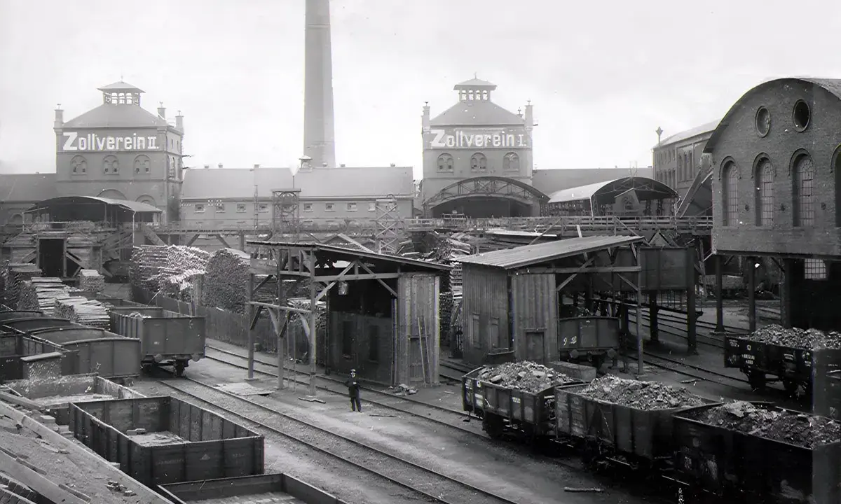 Ein Zeugnis der **hochindustrialisierung**: Zollverein II mit Schornstein, Loren voller Kohle und Holzlager.