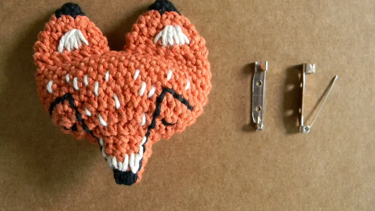 Un adorable zorro naranja tejido a crochet, listo para convertirse en un broche. ¡Perfecto para quienes buscan patrones de broches crochet únicos!