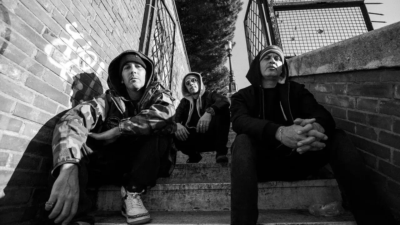 Tre uomini con cappuccio siedono sulle scale, un'atmosfera da musica hip hop famosa.
