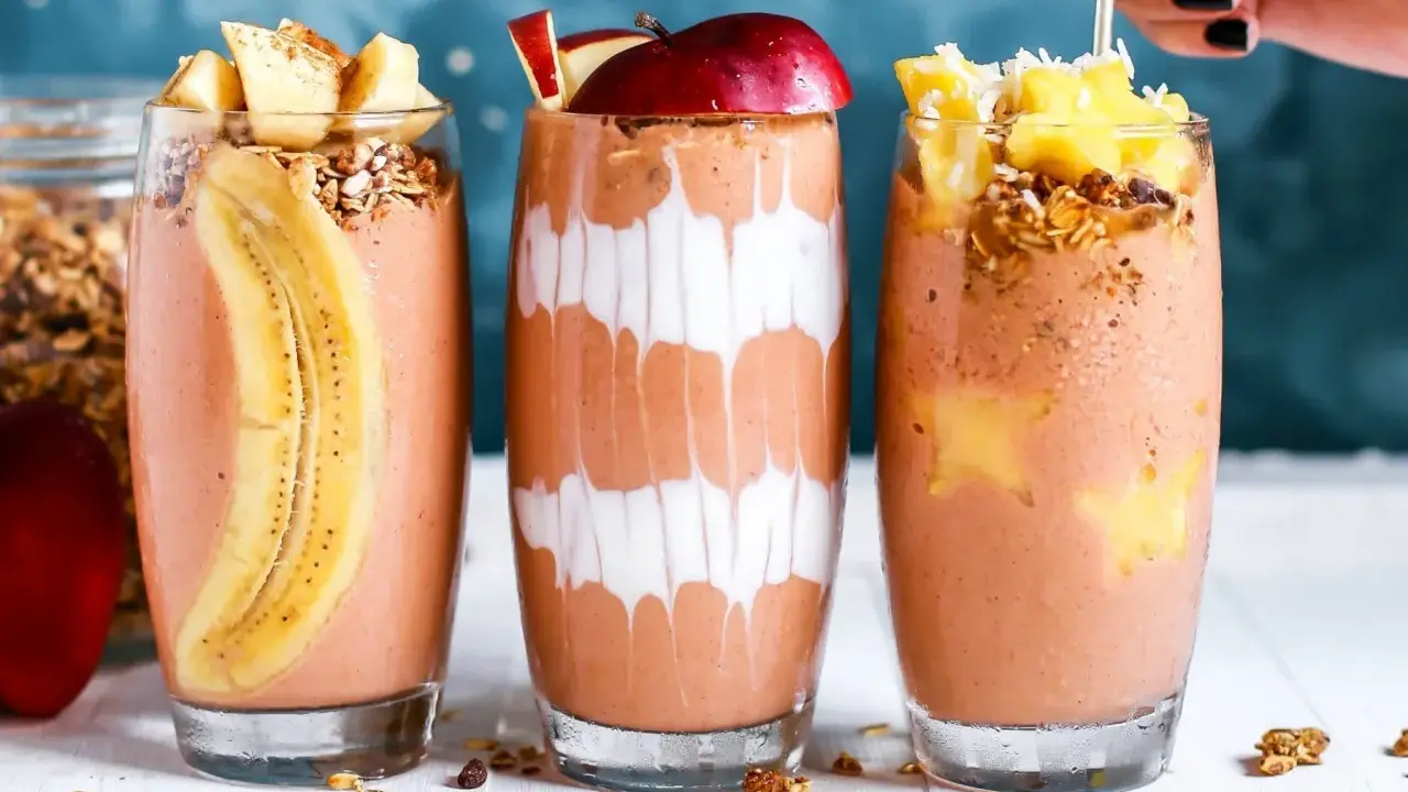 Drei leckere, bunte Smoothies im Glas, garniert mit Früchten und Müsli. Perfekt für den gesunden **Aufbau-Shake** am Morgen.