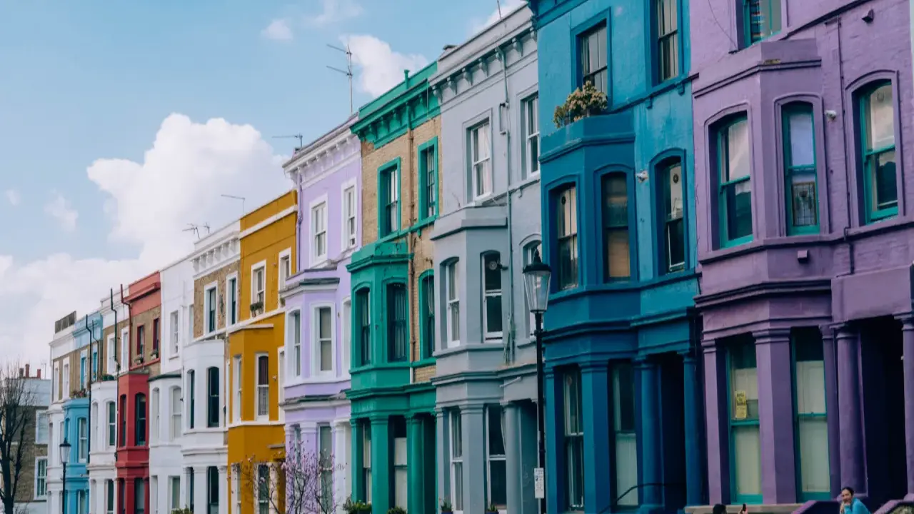 Kolorowe kamienice w Notting Hill w Londynie, tworzące tęczowy rząd pod błękitnym niebem.