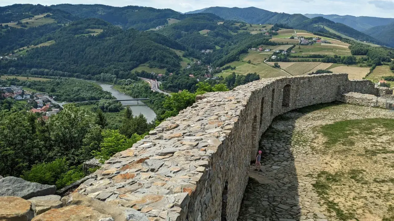 Kamienne mury zamku w Rytrze, z których roztacza się widok na dolinę Dunajca i okoliczne wzgórza. To wspaniałe **rytro atrakcje** dla miłośników historii i przyrody.
