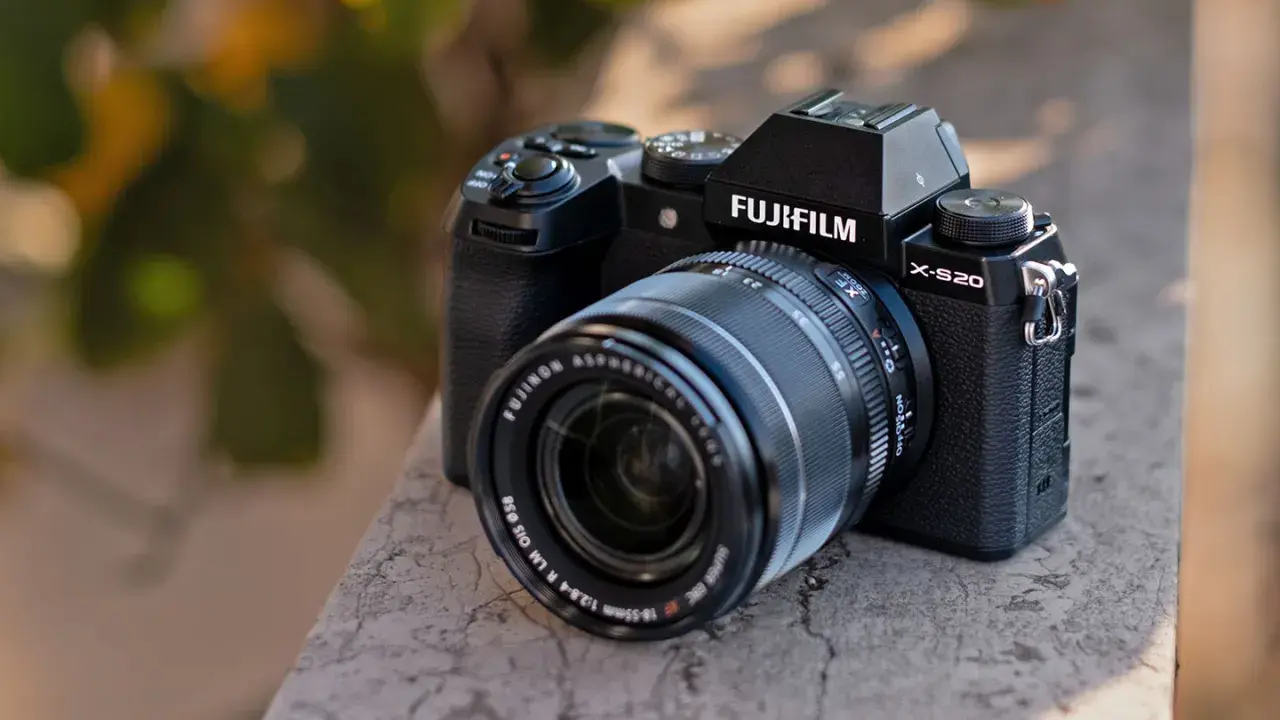 Czarny aparat Fujifilm X-S20 z obiektywem Fujinon leży na kamiennym murku.