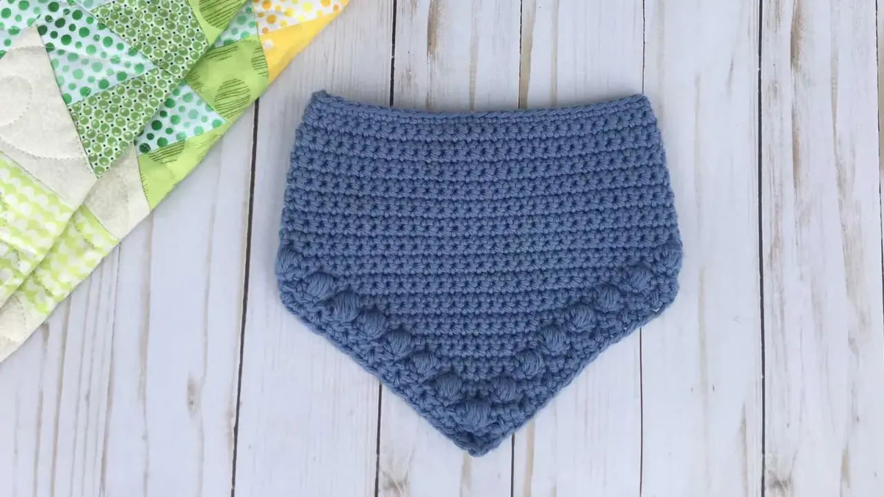 Babero azul tejido a crochet con detalle de pompones. Patrones baberos crochet instrucciones para crear esta linda prenda.